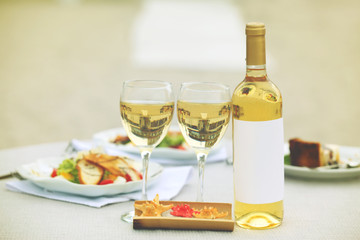 Bottle of luxury wine with tasty salad on white served table