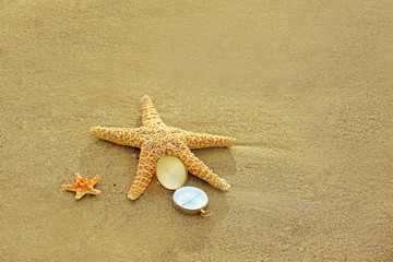 Fototapeta na wymiar Compass with sea stars on sand beach background