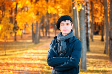 Serious teenage boy in the autumn sunny park