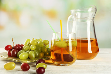 Grape, glass and jug with juice on white table