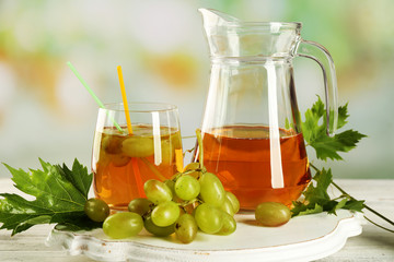 Grape, glass and jug with juice on white table
