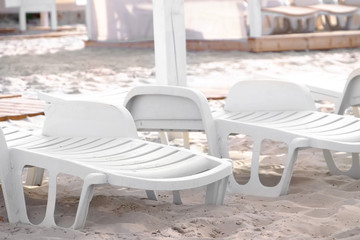 Plastic sunbeds on sandy beach, close up