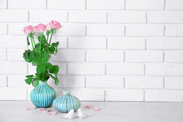 Beautiful roses and vases on brick wall background
