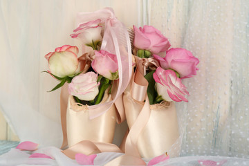 Bouquet of roses in ballet shoes on wooden background