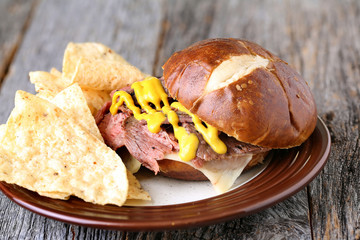 Flank steak sandwich with pretzel bun and mustard