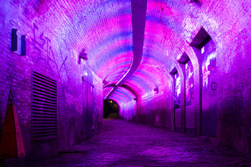 Purple and pink illuminated Ganzemarkt tunnel to Oudegracht in the old city centre of Utrecht,...