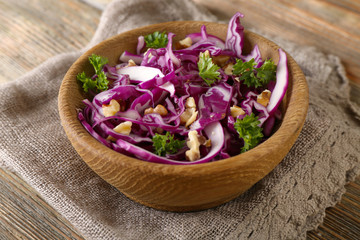 Red cabbage and parsley salad in bowl on wooden table