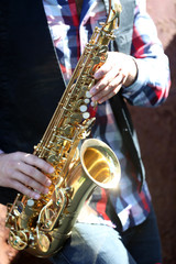 Obraz premium Handsome young man with sax on old brown wall background, close up