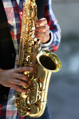 Obraz premium Handsome young man plays sax outdoors, close up
