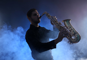 Fototapeta na wymiar Elegant saxophonist plays jazz in blue smoke