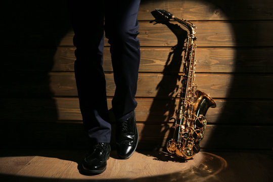 The musician with sax on wooden background, close up