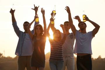 Obraz premium Young people with beer on the riverside