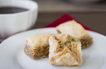 horizontal close up image of some pastry h'orderves in a white plate with a cup of coffee blurred in the background.