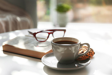 Cup of coffee with biscuits on table in room