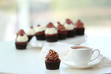 Beautiful chocolate cupcakes and cup of tea,  on table