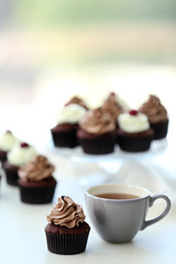 Beautiful chocolate cupcakes and cup of tea,  on table