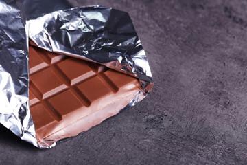 Fototapeta na wymiar Chocolate bar in foil on gray background