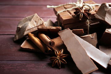 Black chocolate pieces with spices on wooden background