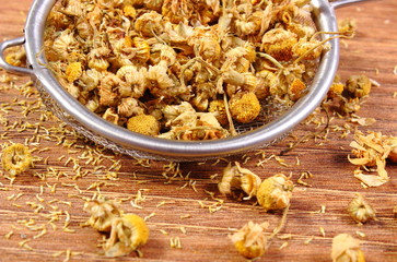 Dried chamomile on metal sieve, alternative medicine
