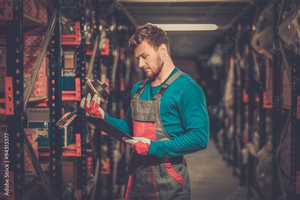 Wall mural Worker on a automotive spare parts warehouse