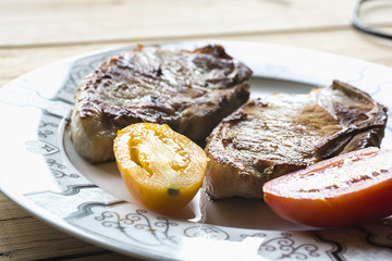 Roast pork with fresh tomatoes on a plate