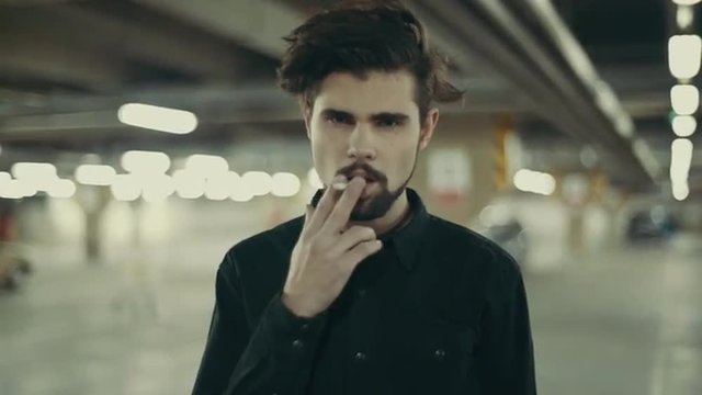 young handsome bearded man smoking cigarette 