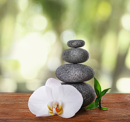 Stack of spa stones with orchid flower on blurred nature background