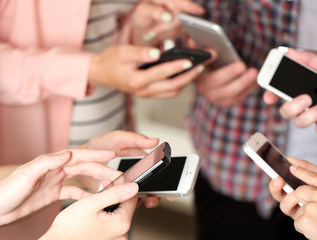 Many hands holding mobile phones close up