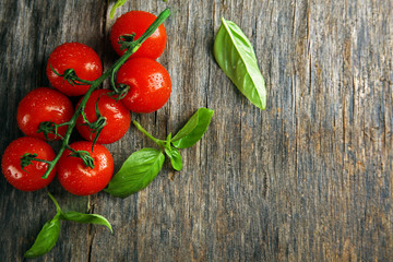 Cherry tomatoes with basil on wooden table close up