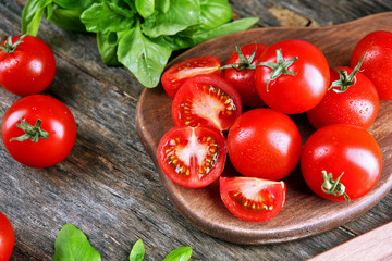 Cherry tomatoes with basil on wooden table close up