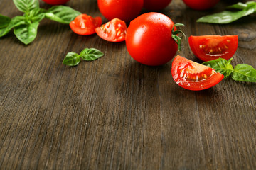 Fresh tomatoes with basil on wooden table close up