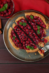Tart with raspberries on tray, on wooden background