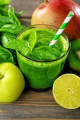 Green healthy juice with fruits and herbs on table close up