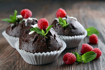 Delicious chocolate cupcakes with berries and fresh mint on wooden table close up