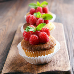 Delicious cupcakes with berries and fresh mint on wooden table close up