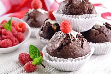Delicious chocolate cupcakes with berries and fresh mint on wooden table close up