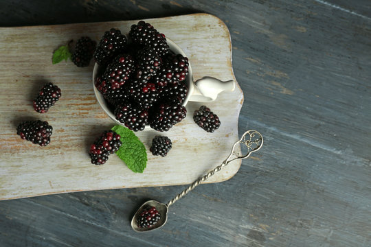 Heap of sweet blackberries with mint in cup on table close up