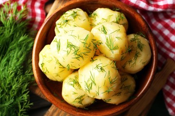 Boiled potatoes with greens in bowl on table close up