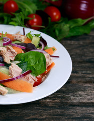 Tuna salad with Spinach, rocket, red ruby chard, tomatoes, cucumbers, carrot, red onion on old wooden table