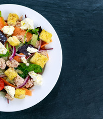 Tuna salad with Spinach, rocket, red ruby chard, tomatoes, cucumbers, white cheese, carrot, red onion, croutons on old blue stone background