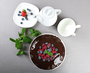 Delicious chocolate cake with summer berries on grey tablecloth, top view