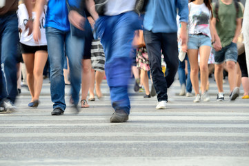 Motion blurred pedestrians crossing sunlit street