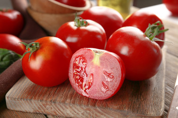 Red tomatoes on cutting board on wooden background