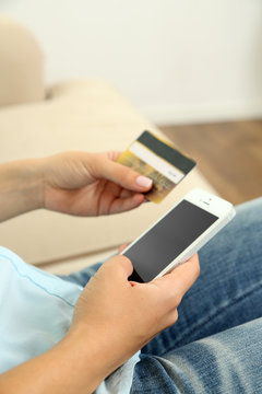 Female's hands hold credit card and cellphone, close up