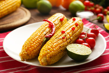 Grilled corn served with tomatoes and lime