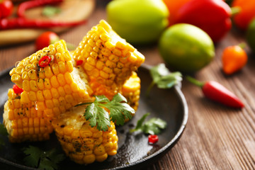 Tasty grilled corn and vegetables on black crockery