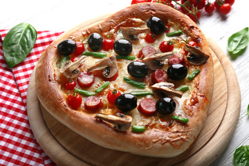 Heart shaped tasty pizza and red checked cotton serviette on wooden background