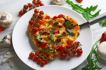 Heart shaped decorated with vegetables pizza on white plate on wooden background