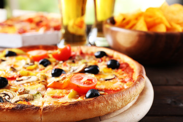 Pizza served with beer on wooden table