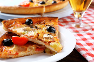 Sliced pizza served with beer on wooden table